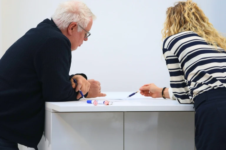 Two colleagues reviewing material and discussing choices at the table.