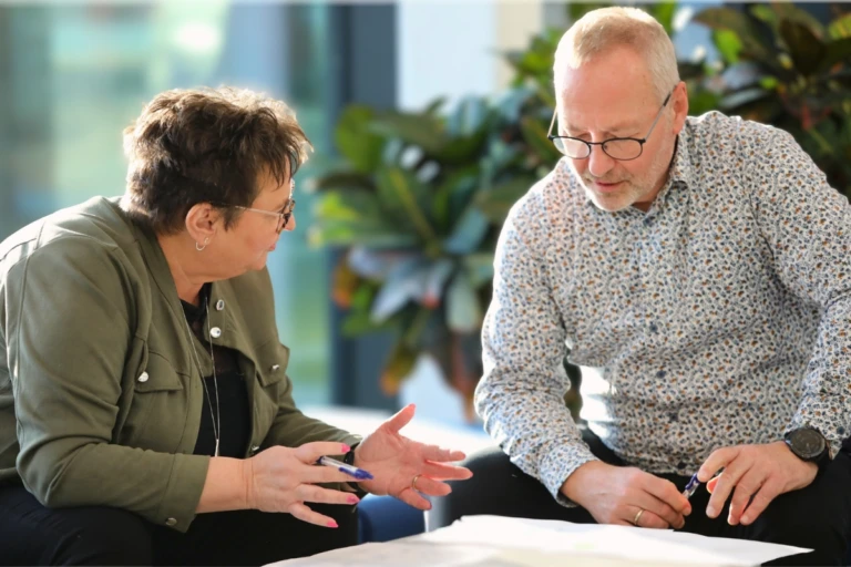Two colleagues reviewing documents and discussing a decision.